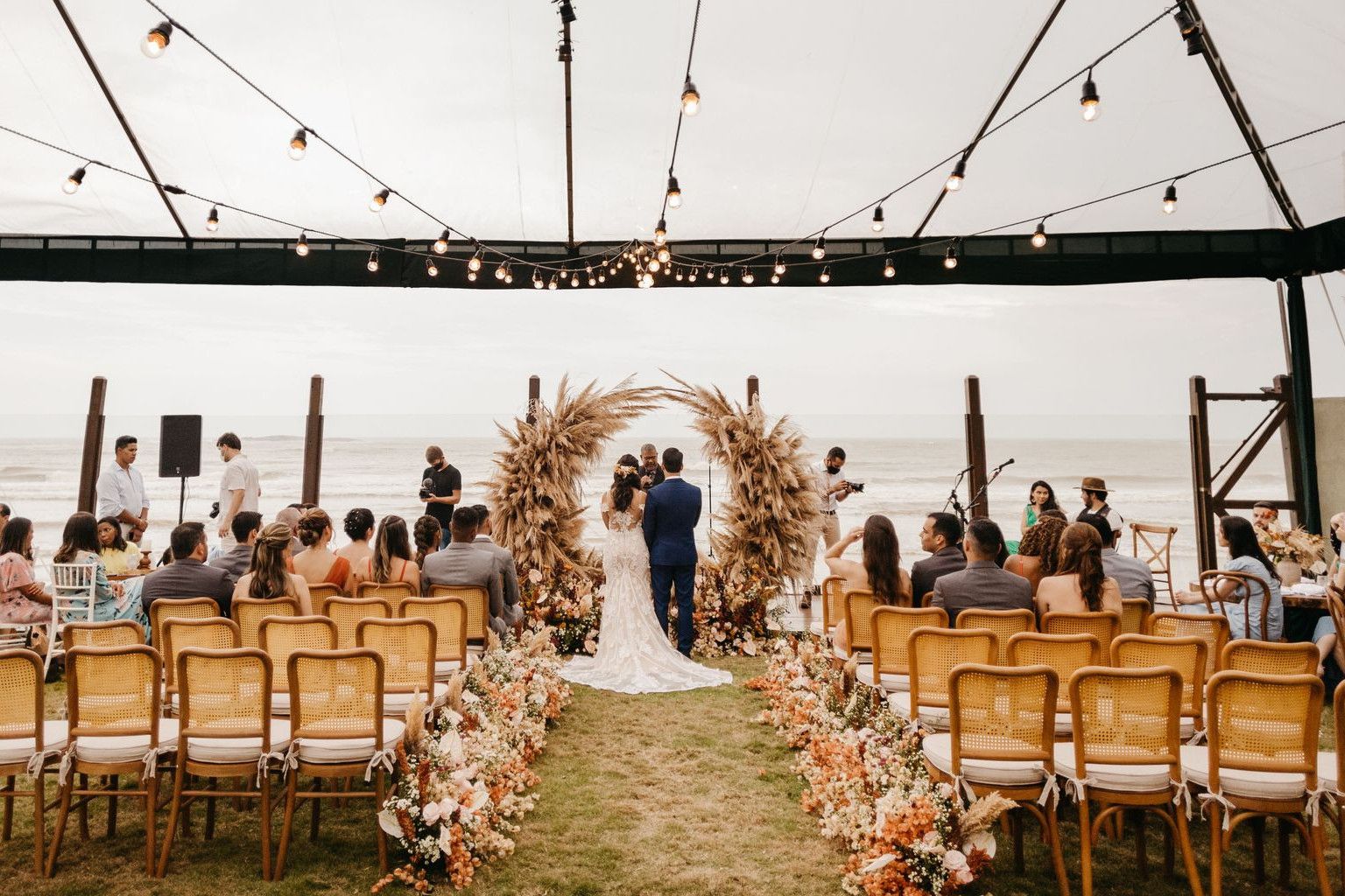 A picturesque wedding ceremony held outdoors under a canopy by the sea. Perfect setting for a romantic event.